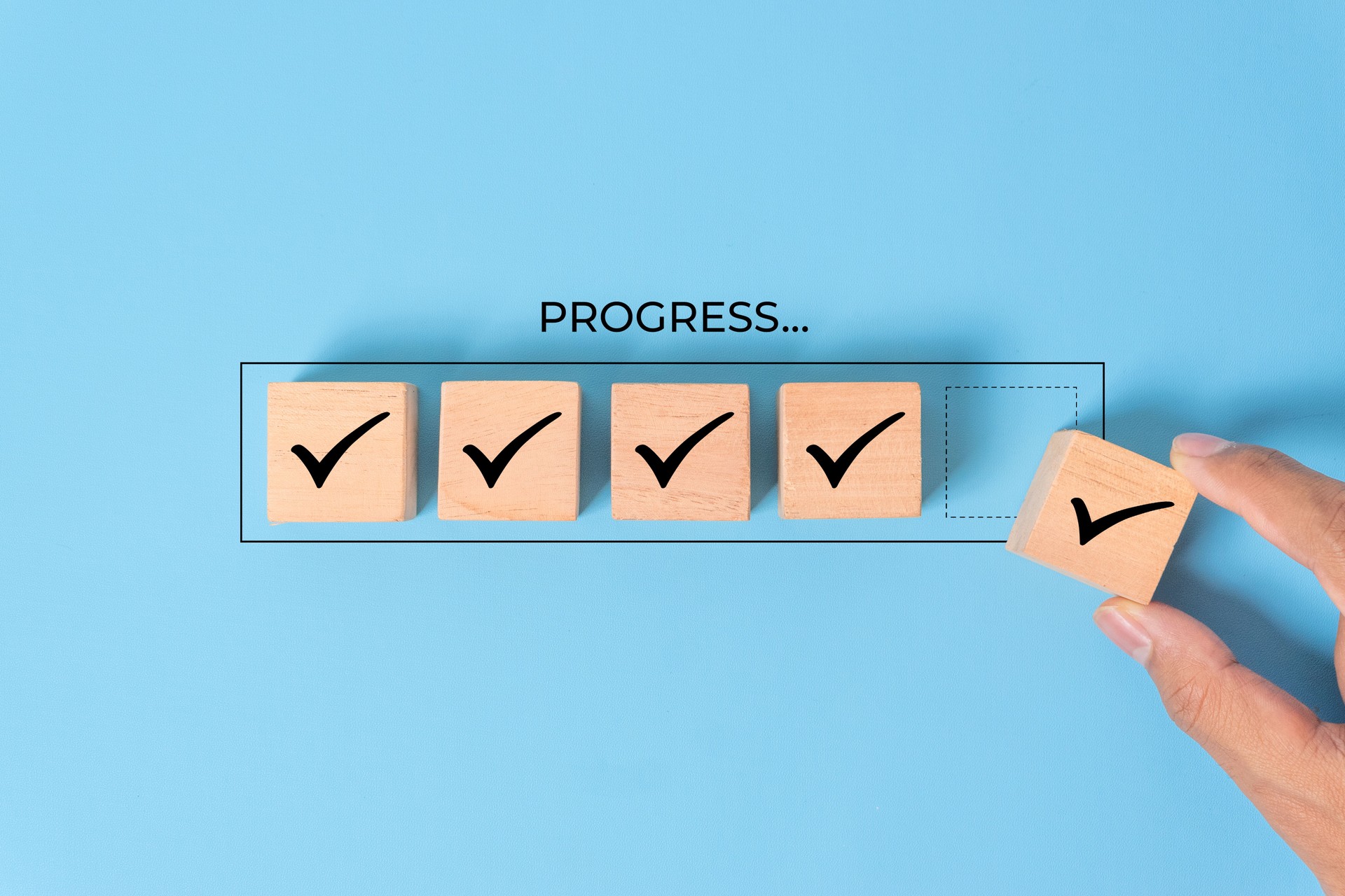 Checklist and task progress tracking concept. A hand placing the final checkmark on wooden blocks in a progress bar, task completion, productivity, goal setting, and efficient project management